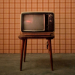 Televisore anni '60 su sgabello con sfondo a quadretti - 70 anni di tv
