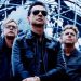 Uomo in rimo piano con altri due uomini dietro - Depeche Mode