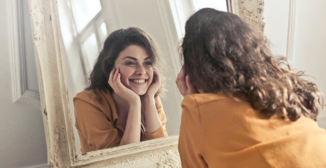 Ragazza sorridente allo specchio - Libri sulla felicità