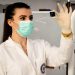 Dottoressa con camice e mascherina con in mano un vetrino - giovani medici