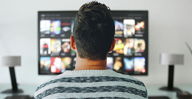 Uomo di spalle davanti a schermo grande tv - serie tv