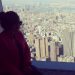 Ragazza affacciata a vetrata panoramica su New York