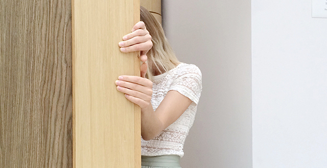 Donna che si nasconde dietro a porta - Sindrome dell'impostore
