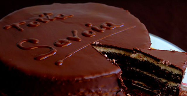 Torta Savoia ricoperta di cioccolato da cui si taglia una fetta
