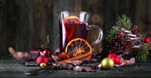 Bicchiere di vin brulé tra fetta di arancia, aghi di pino e palline di Natale