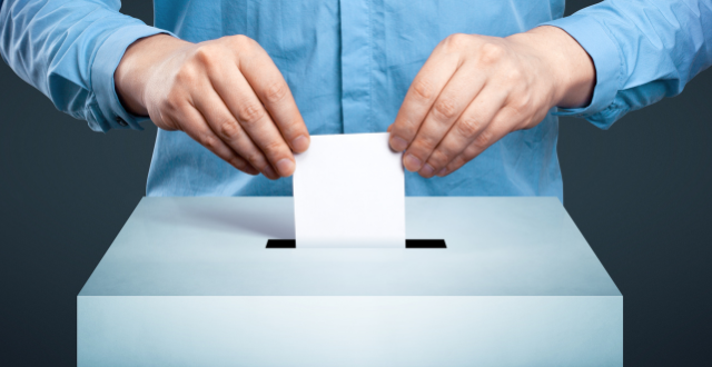 Mani che infilano foglio in urna elettorale - referendum
